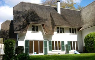 jolie maison avec toit en chaume et murs blancs