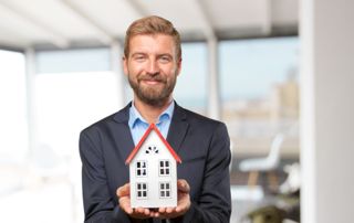 Agent immobilier avec une maison miniature dans les mains