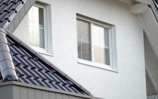 Façade blanche avec châssis blanc et morceau de toiture en tuiles