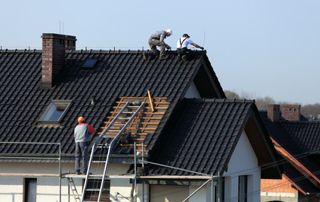 couvreurs travaillant sur un toit incliné en tuiles