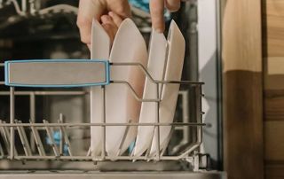 une personne range des assiettes dans un lave-vaisselle